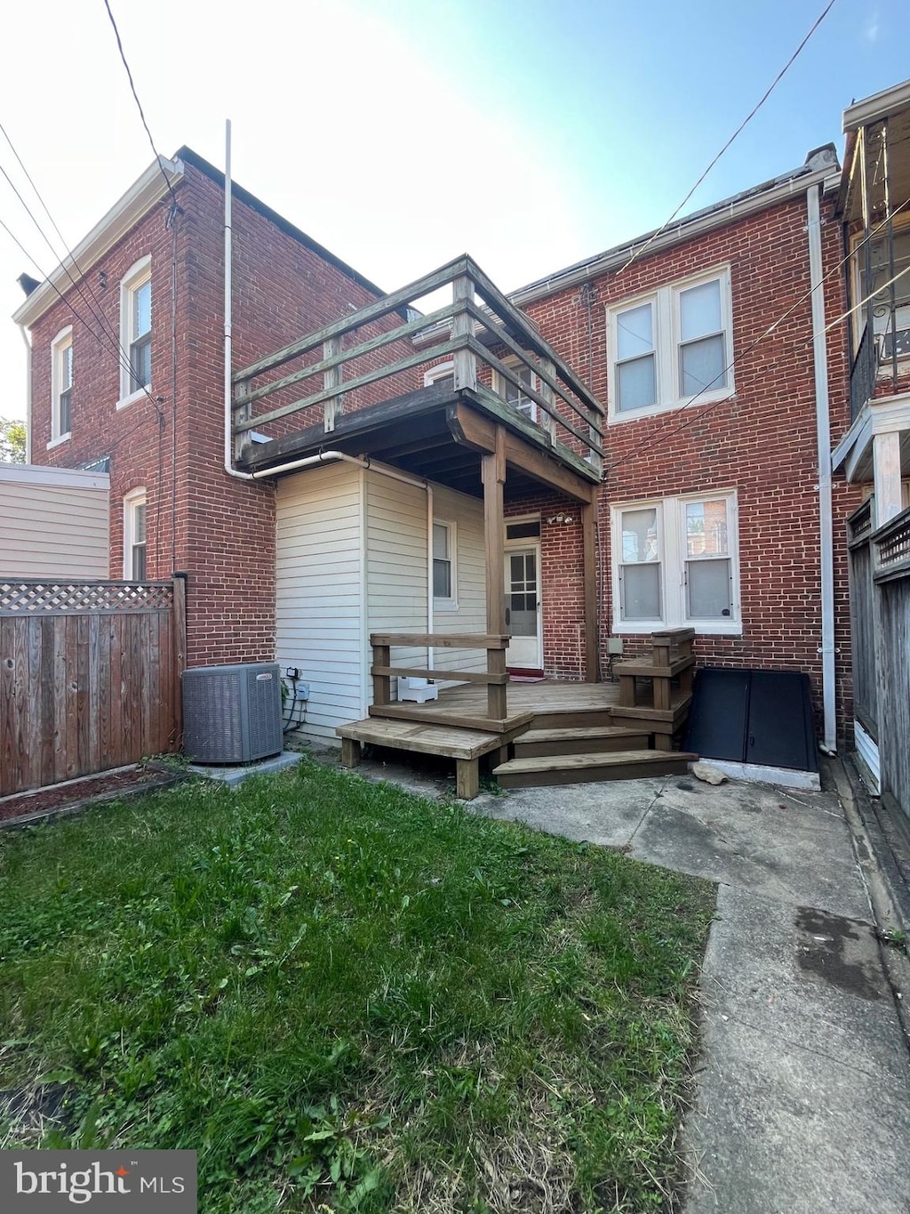 rear view of house with brick siding, a balcony, central AC unit, and a wooden deck