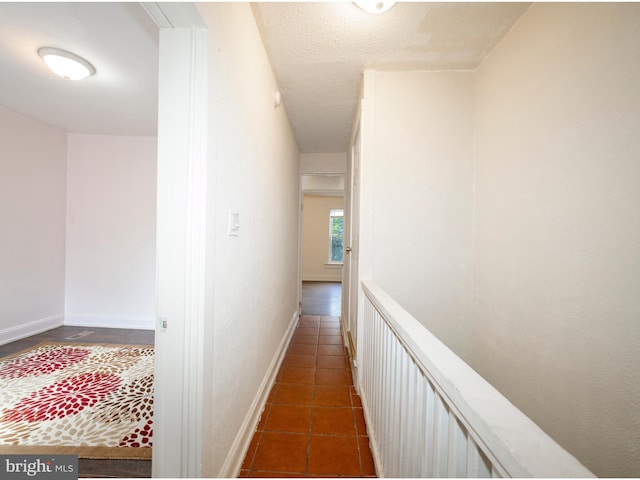 corridor featuring baseboards and dark tile patterned floors