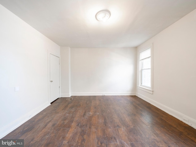 empty room featuring dark wood finished floors and baseboards