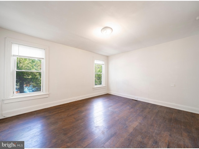 unfurnished room with dark wood-style floors and baseboards