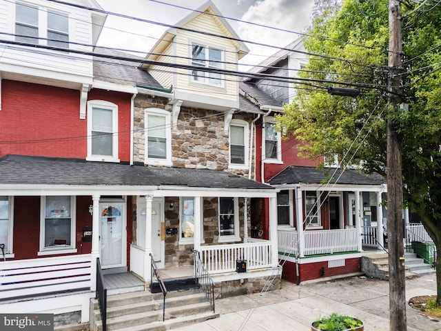 townhome / multi-family property with covered porch and stone siding