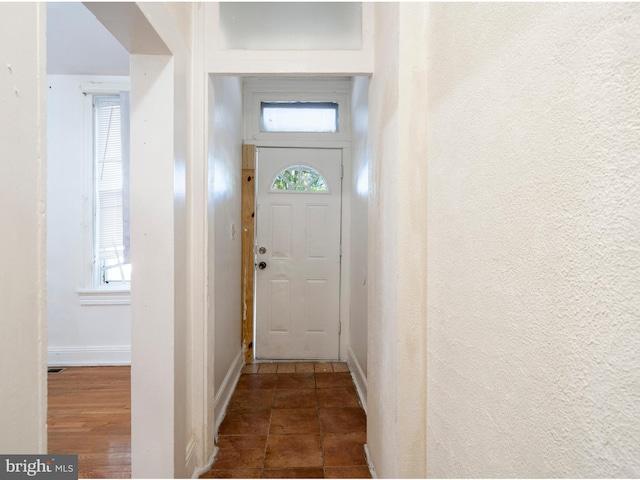 entryway featuring baseboards, tile patterned floors, and a textured wall