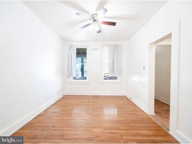 spare room featuring light wood-style floors, baseboards, and a ceiling fan