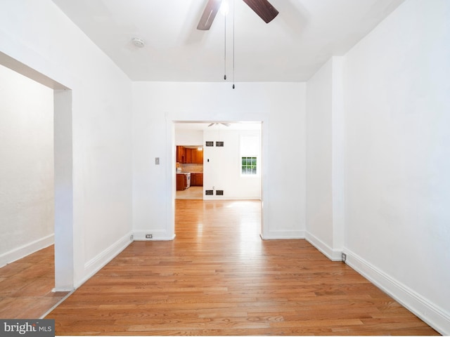 unfurnished room with ceiling fan, light wood-style floors, baseboards, and a smoke detector