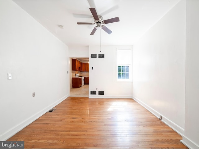unfurnished living room featuring ceiling fan, light wood-style flooring, and baseboards
