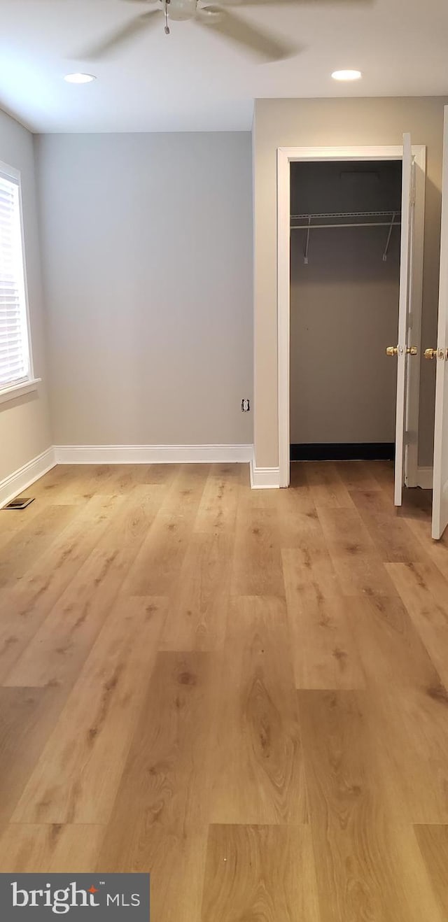 unfurnished bedroom featuring light wood finished floors, baseboards, ceiling fan, and visible vents