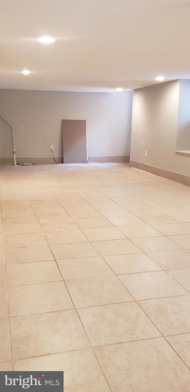 empty room featuring light tile patterned flooring, baseboards, and recessed lighting
