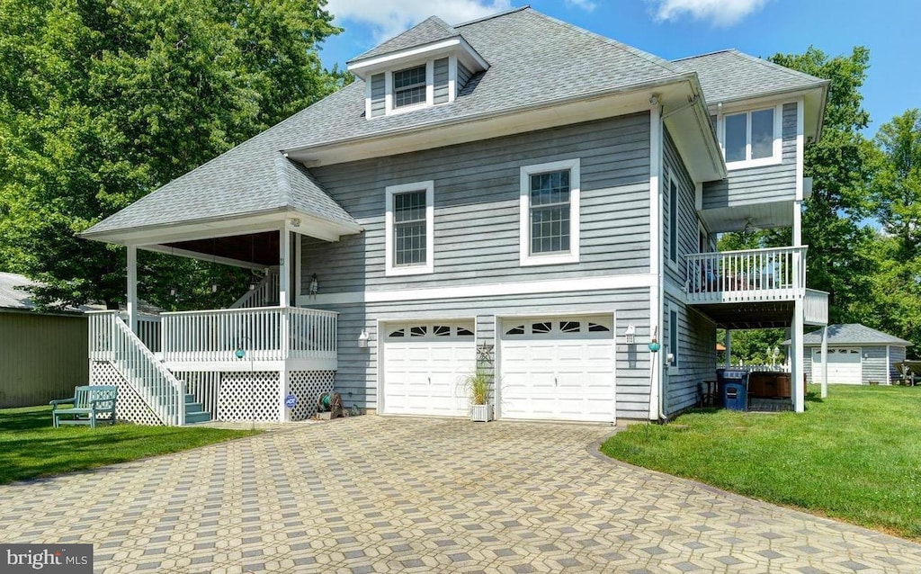 view of front of home with an attached garage, a front yard, roof with shingles, and driveway