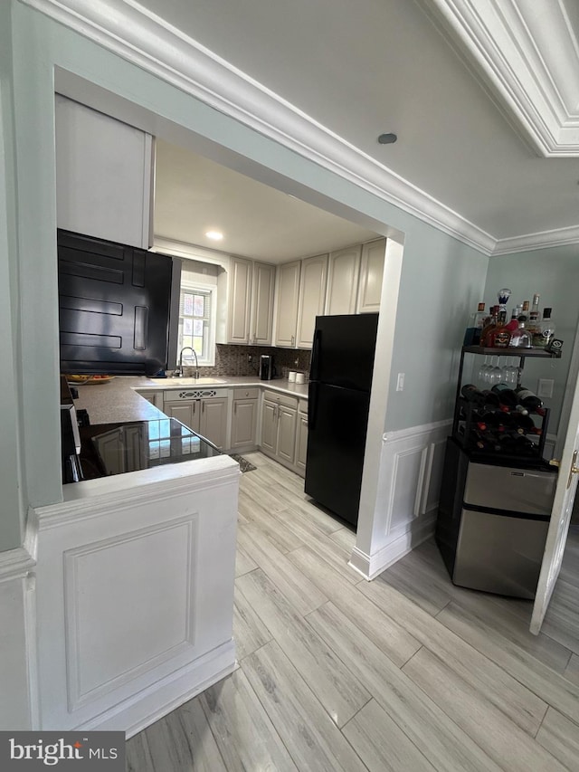 18 River Ln, Levittown, PA 19055 - kitchen with freestanding refrigerator, crown molding, light wood-style floors, a wainscoted wall, and backsplash