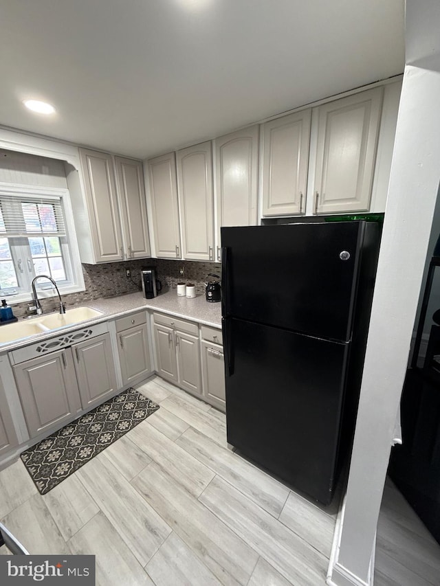18 River Ln, Levittown, PA 19055 - kitchen with freestanding refrigerator, a sink, light countertops, light wood finished floors, and decorative backsplash