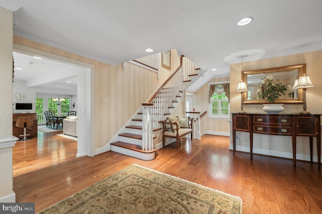 staircase featuring baseboards, crown molding, healthy amount of natural light, wood finished floors, and recessed lighting