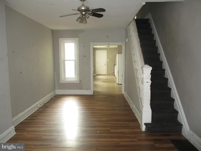 interior space featuring a ceiling fan, stairs, baseboards, and wood finished floors