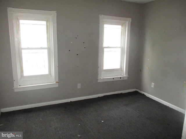 unfurnished room featuring dark colored carpet and baseboards