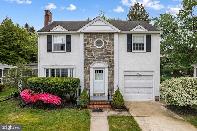 view of front of home featuring an attached garage, a chimney, driveway, stone siding, and stucco siding