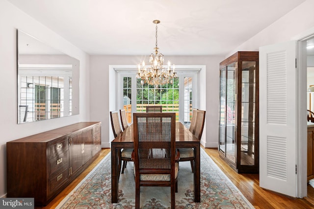 dining area with a chandelier, light wood-style flooring, and baseboards