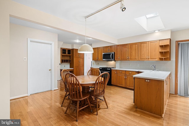 kitchen featuring stainless steel microwave, black gas range, open shelves, a skylight, and a sink