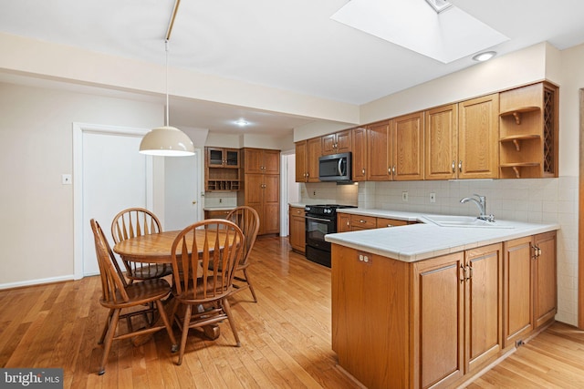 kitchen with stainless steel microwave, black range with gas cooktop, a sink, a skylight, and open shelves