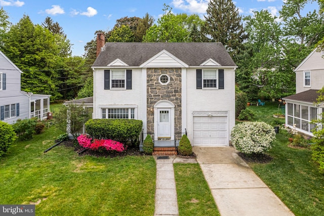 view of front facade featuring stone siding, driveway, an attached garage, a chimney, and a front lawn