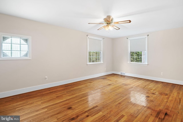 empty room with light wood finished floors, baseboards, and a ceiling fan