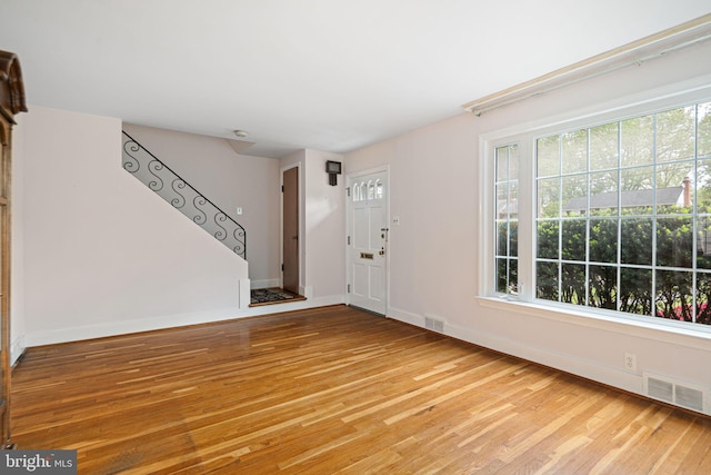 foyer entrance with light wood-type flooring, baseboards, and stairway