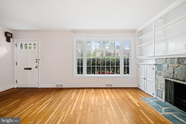 unfurnished living room with light wood finished floors, a fireplace, and baseboards