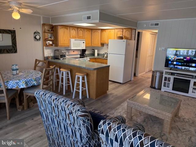 11 71st St Unit 102, Ocean City, MD 21842 - kitchen featuring white appliances, light wood-style flooring, ceiling fan, a peninsula, and wood walls