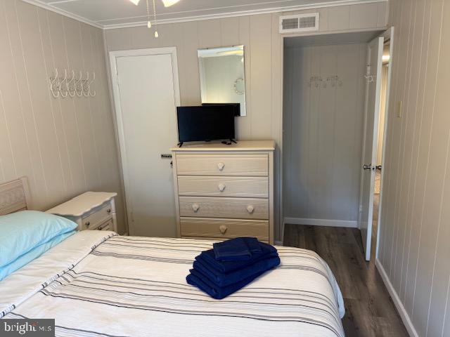 11 71st St Unit 102, Ocean City, MD 21842 - bedroom with dark wood-type flooring, ornamental molding, and wooden walls