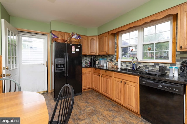 kitchen featuring brown cabinets, a sink, dark stone counters, black appliances, and decorative backsplash