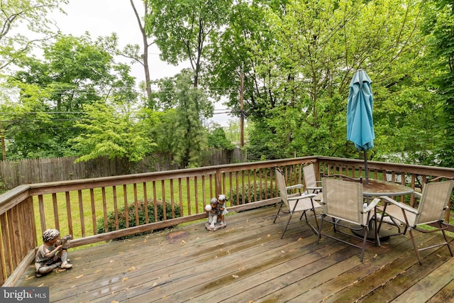 wooden terrace with outdoor dining area and fence