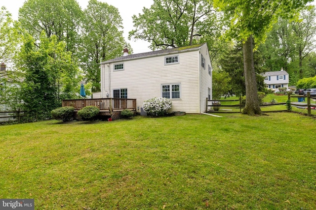 back of property featuring a yard, fence, and a deck