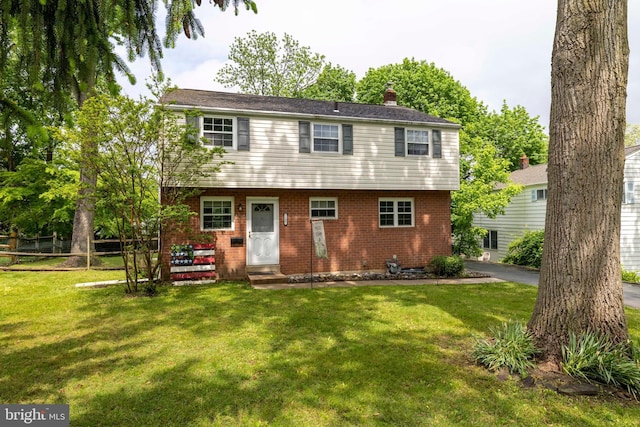 back of house with a lawn, a chimney, and brick siding