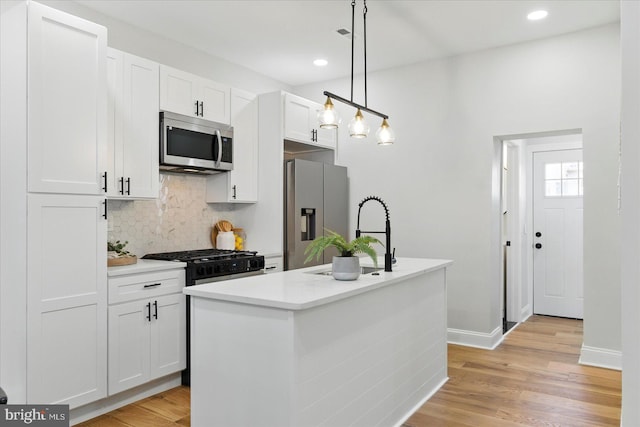 2424 W Lanvale St, Baltimore, MD 21216 - kitchen with stainless steel appliances, a sink, tasteful backsplash, white cabinetry, and light wood finished floors