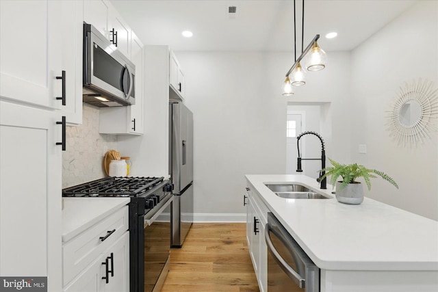 2424 W Lanvale St, Baltimore, MD 21216 - kitchen with stainless steel appliances, a sink, backsplash, an island with sink, and light wood-type flooring