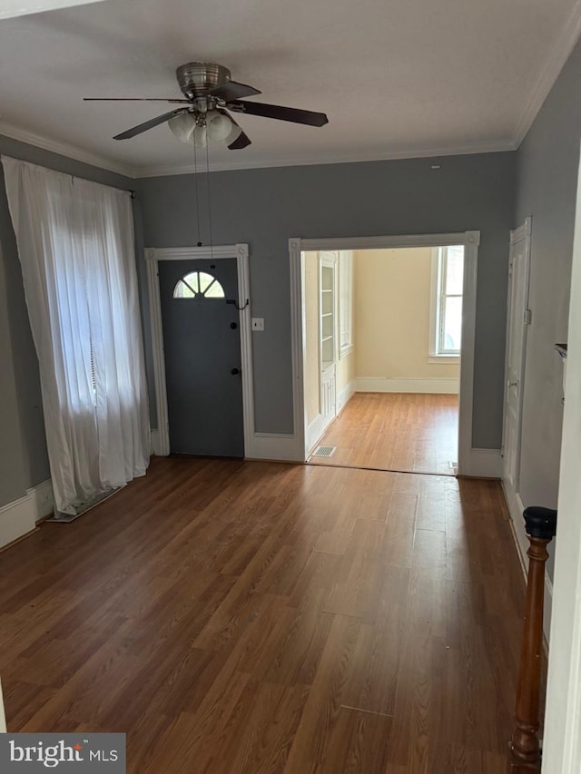 entryway with ceiling fan, wood finished floors, ornamental molding, and baseboards