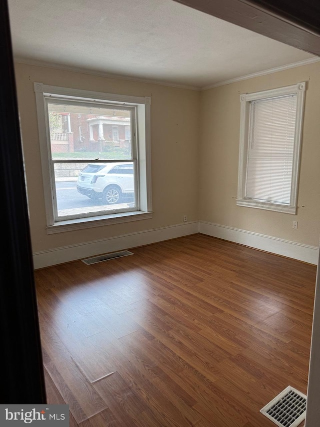 spare room featuring ornamental molding, wood finished floors, and baseboards
