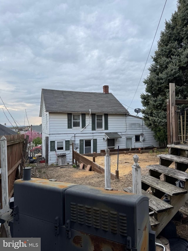 rear view of property with a chimney and fence