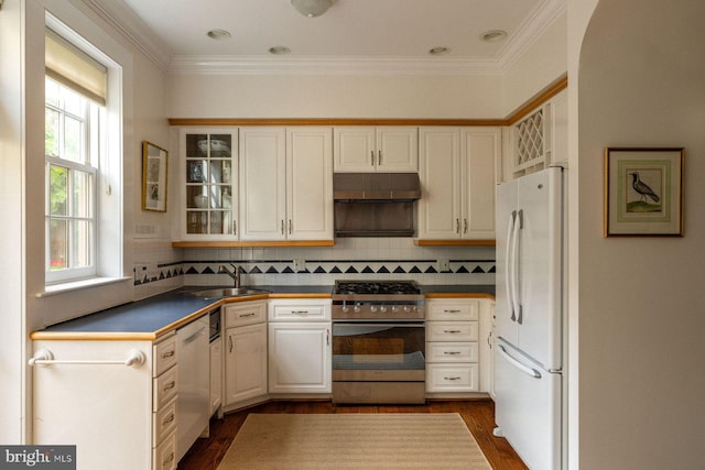 kitchen featuring white appliances, a sink, ornamental molding, dark wood-style floors, and glass insert cabinets