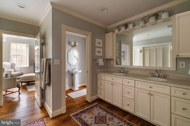full bath featuring double vanity, wood finished floors, crown molding, and baseboards