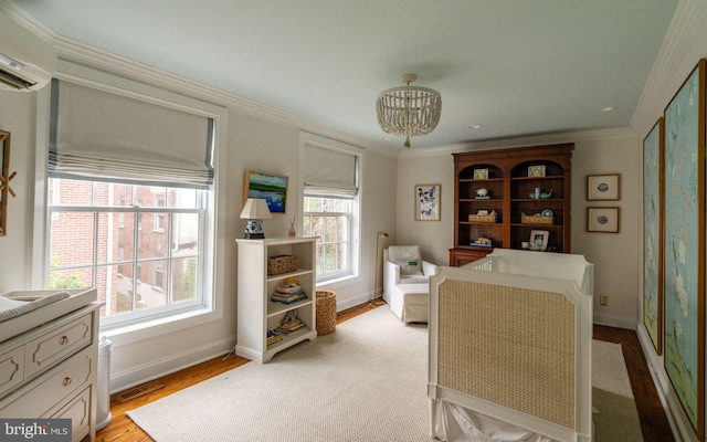 living area featuring a chandelier, a wall unit AC, crown molding, light wood-style flooring, and baseboards