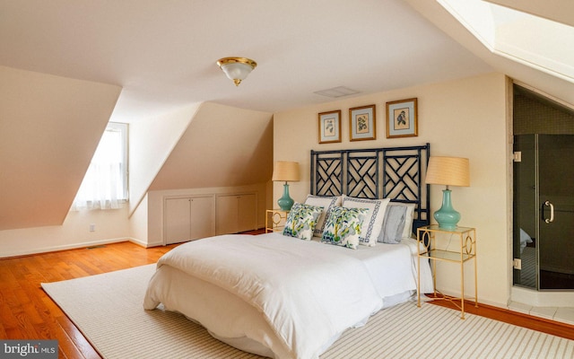 bedroom with lofted ceiling, wood finished floors, and baseboards