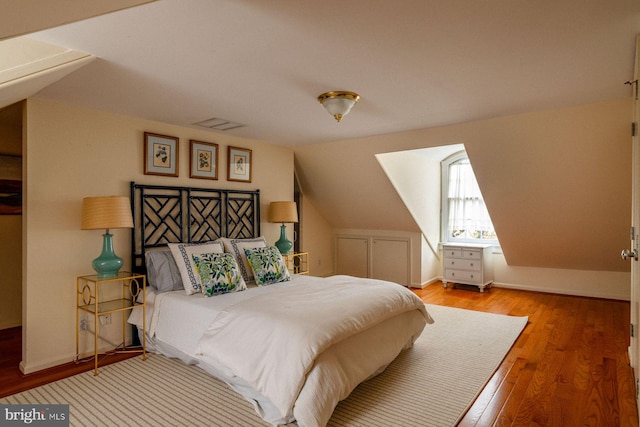 bedroom featuring wood finished floors, baseboards, and lofted ceiling