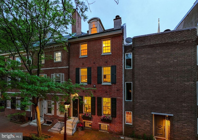 rear view of house with brick siding and a chimney