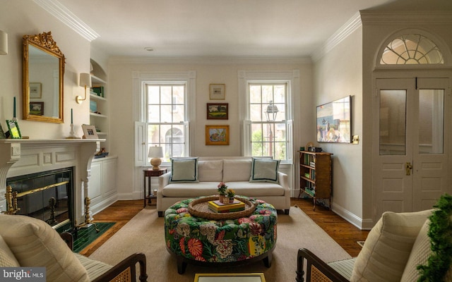 living area with ornamental molding, baseboards, a fireplace with flush hearth, and wood finished floors