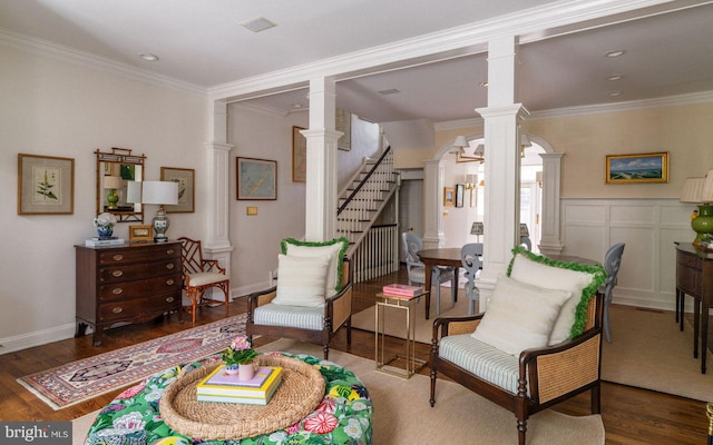 living area featuring ornate columns, stairs, wood finished floors, and crown molding