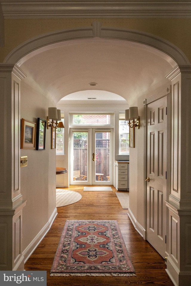 corridor with arched walkways, french doors, and wood finished floors