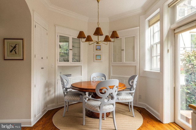 dining space with plenty of natural light, crown molding, light wood finished floors, baseboards, and arched walkways