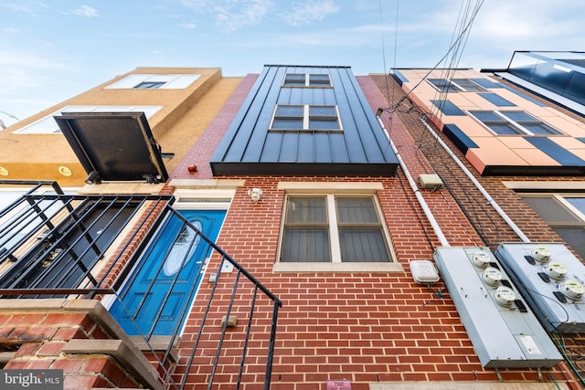 exterior space with a standing seam roof and brick siding
