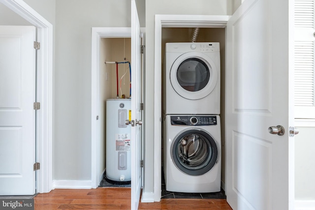 laundry room featuring water heater, stacked washing maching and dryer, laundry area, and wood finished floors