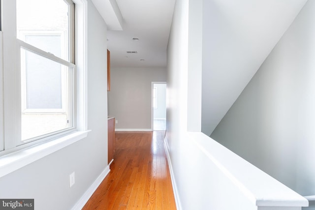 hallway featuring baseboards, light wood-style flooring, and visible vents