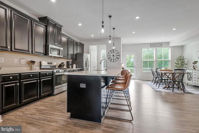 14540 Grace Kellen Ave, Brandywine, MD 20613 - kitchen featuring stainless steel appliances, a sink, wood finished floors, a kitchen island with sink, and light countertops
